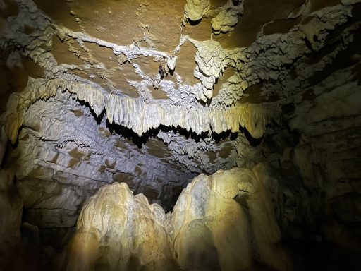 Formaciones de estalactitas y estalagmitas en una cueva iluminada suavemente.